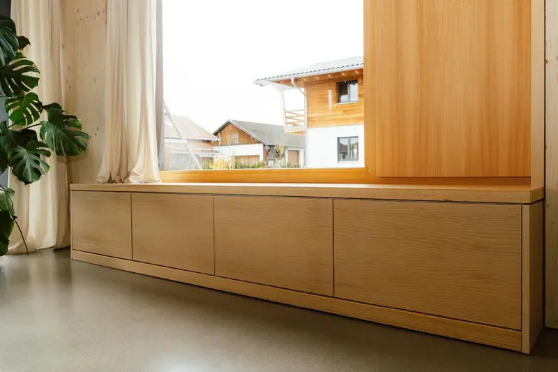Sideboard aus hellem Holz vor einer Fensterfront im Holzhaus im Allgäu